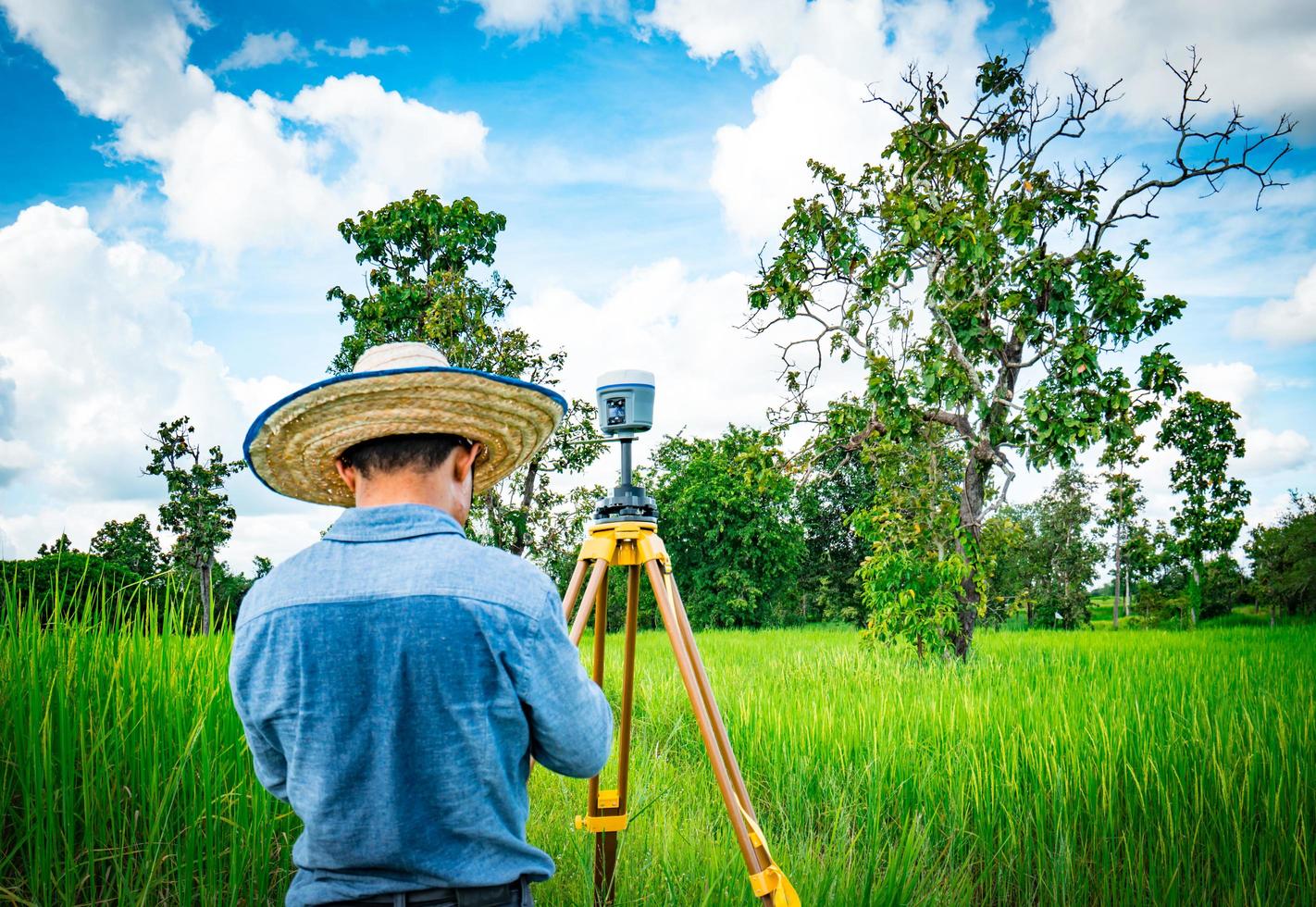 engenheiro inteligente asiático ou agrimensor trabalhando na tela do controlador para levantamento de terras no campo de arroz, tailândia. instrumento de levantamento gps. equipamentos gps. levantamento de terra para o mapa. as pessoas trabalham em bom ambiente. foto