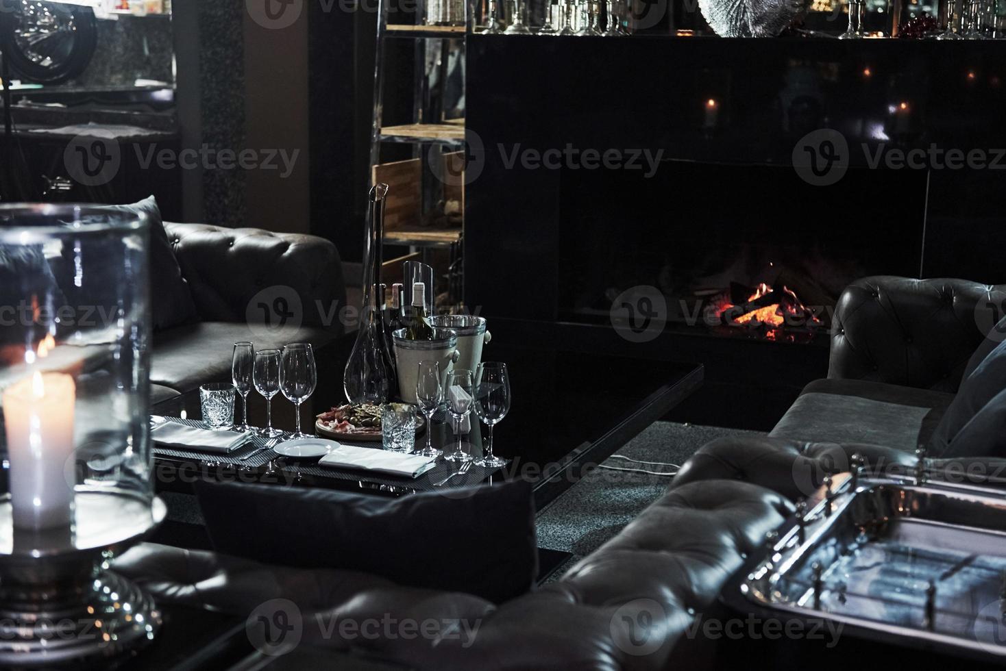 lugar calmo no restaurante com mesa cheia de taças de champanhe e bela lareira foto