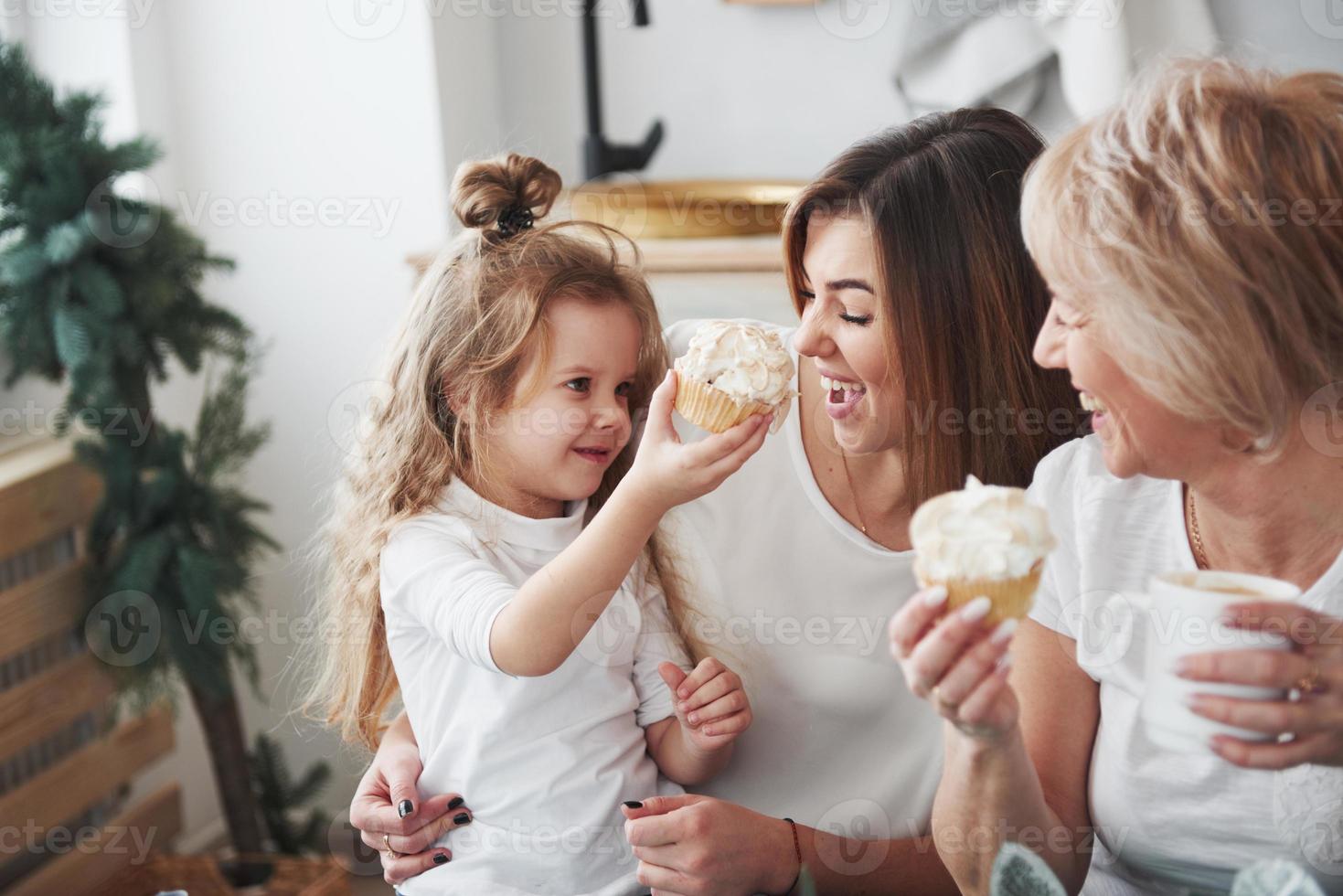 olha esse bolo delicioso. mãe, avó e filha se divertindo na cozinha foto