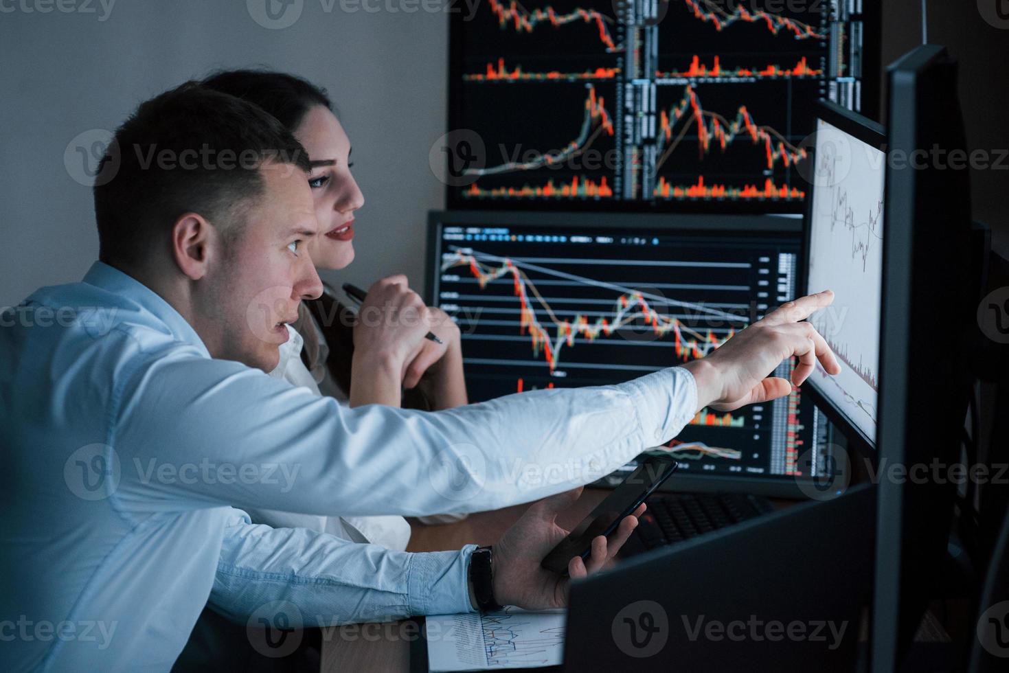 equipe de corretores da bolsa está conversando em um escritório com várias telas de exibição foto