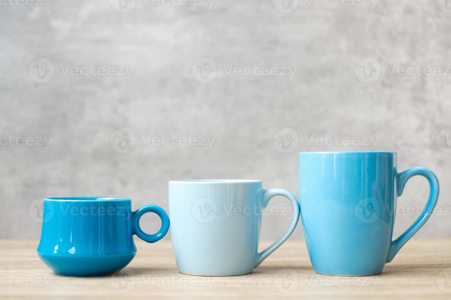 xícara de café azul e caneca de chá no fundo da mesa de madeira pela manhã, espaço de cópia em branco para texto. dia internacional do café e conceito de rotina diária foto