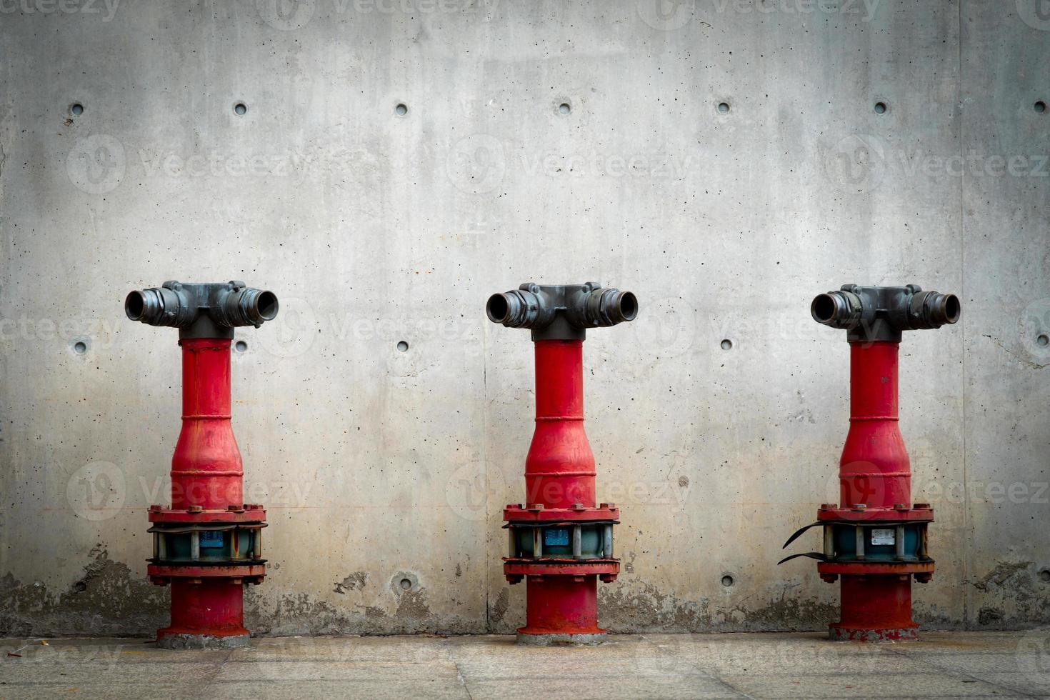 três bombas de segurança contra incêndio no piso de cimento do edifício de concreto. sistema de dilúvio do sistema de combate a incêndios. encanamento de proteção contra incêndio. bomba de incêndio vermelha na frente da parede de concreto. bomba de segurança contra incêndio de alta pressão. foto