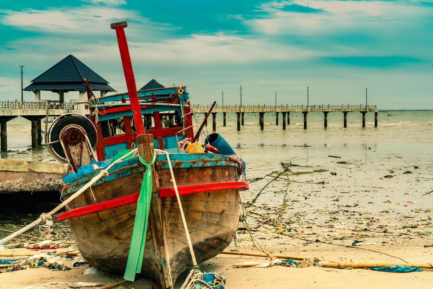 barco de pesca na praia de areia perto da ponte e do mar. relaxamento no paraíso tropical praia e conceito de resort. lixo na praia. poluição ambiental costeira. problemas ambientais marinhos. foto