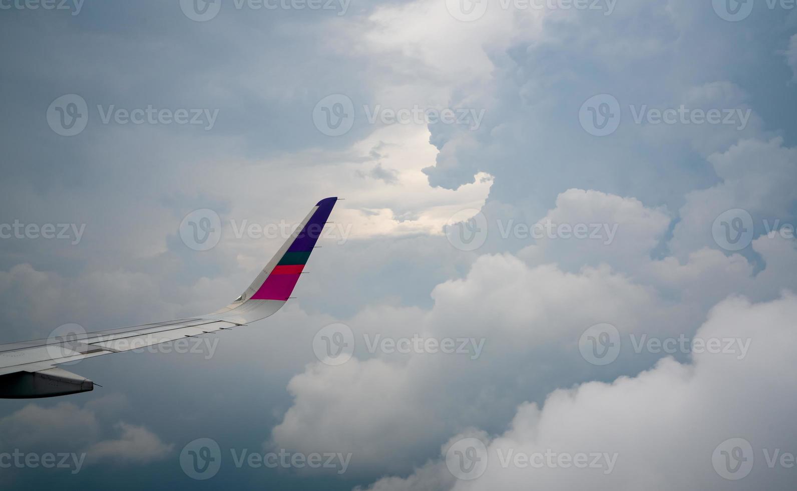 asa de avião sobre a cidade. avião voando no céu azul. vista panorâmica da janela do avião. voo comercial da companhia aérea pela manhã com luz solar. asa de avião acima das nuvens. conceito de mecânica de voo. foto