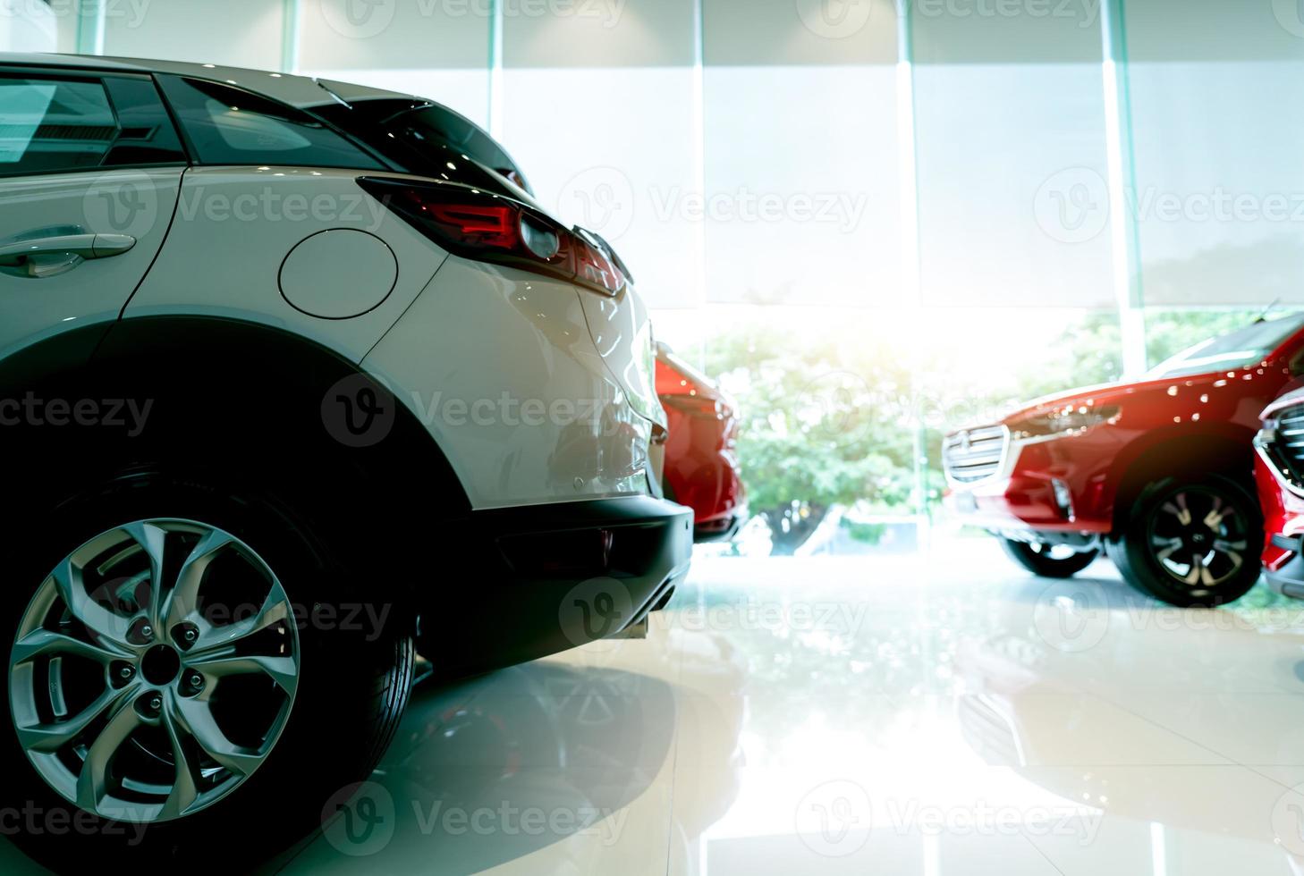 carro suv de luxo branco estacionado no showroom moderno e carro vermelho turva. concessionária de carros e conceito de locação de automóveis. indústria automobilística. interior da sala de exposições. Vendo estoque de carros novos. edifício de vidro do showroom. foto