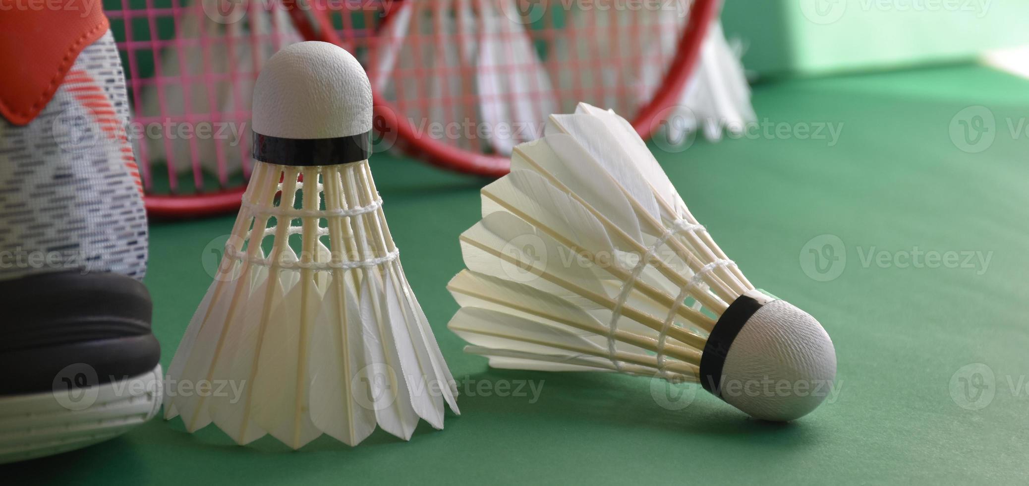 equipamentos de esporte de badminton no chão verde de petecas de quadra de badminton, raquetes, sapatos, foco seletivo em petecas, esporte de badminton jogando amante em todo o conceito do mundo. foto