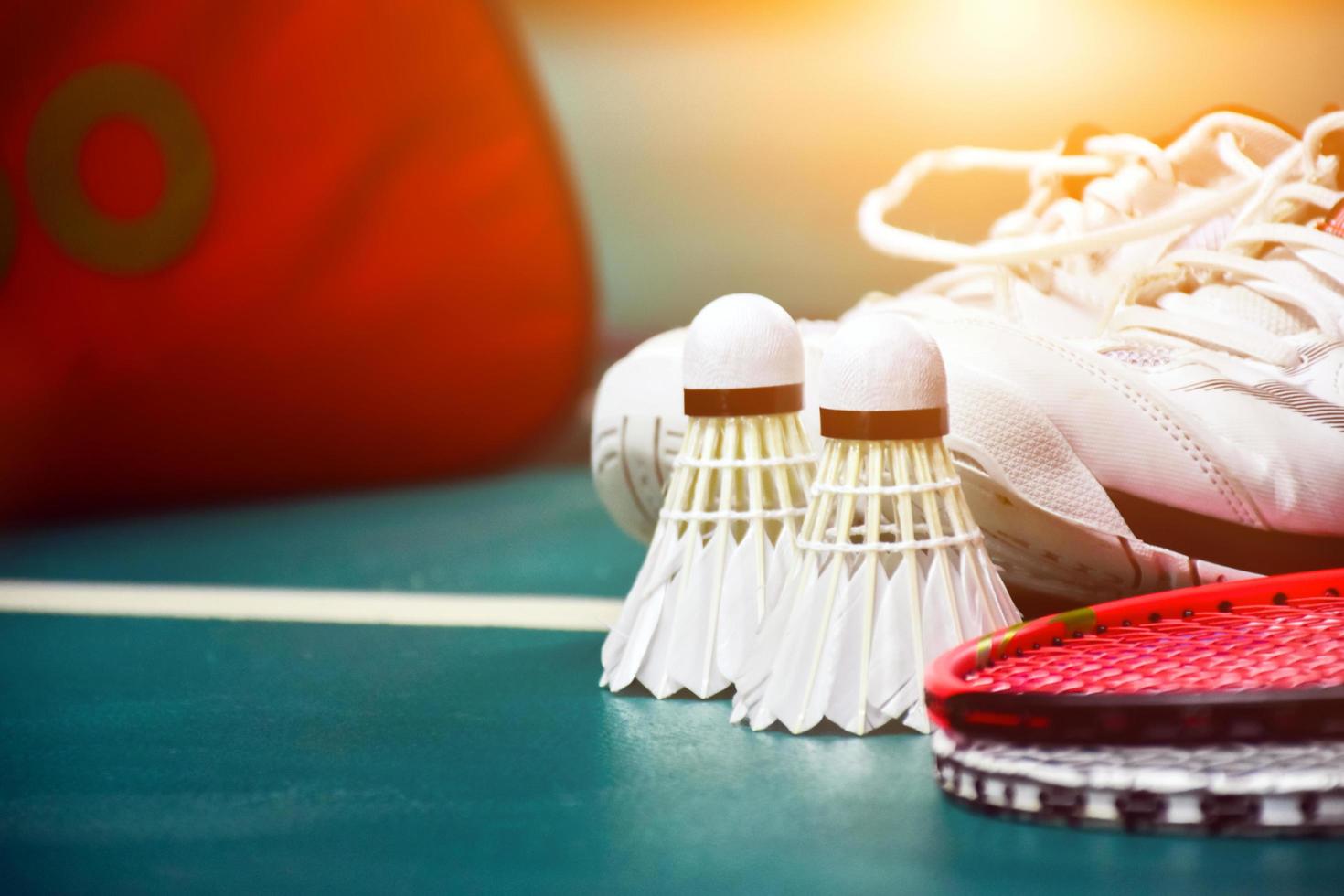 equipamentos de esporte de badminton em petecas de piso verde, raquetes, sapatos, foco seletivo em petecas, conceito de amante de jogo de esporte de badminton. foto