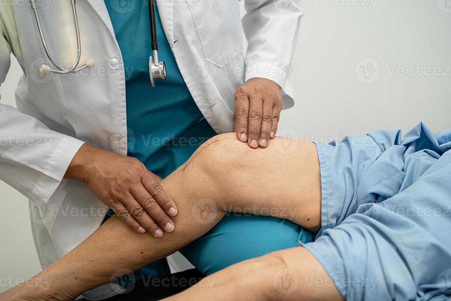 Médico fisioterapeuta examinando, massageando e tratando o joelho e a perna do paciente sênior no hospital de enfermagem da clínica médica ortopedista. foto