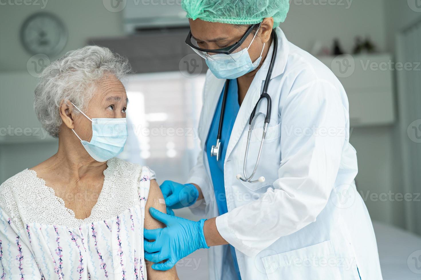 mulher idosa asiática sênior usando máscara facial recebendo vacina de covid-19 ou coronavírus pelo médico fazer injeção. foto