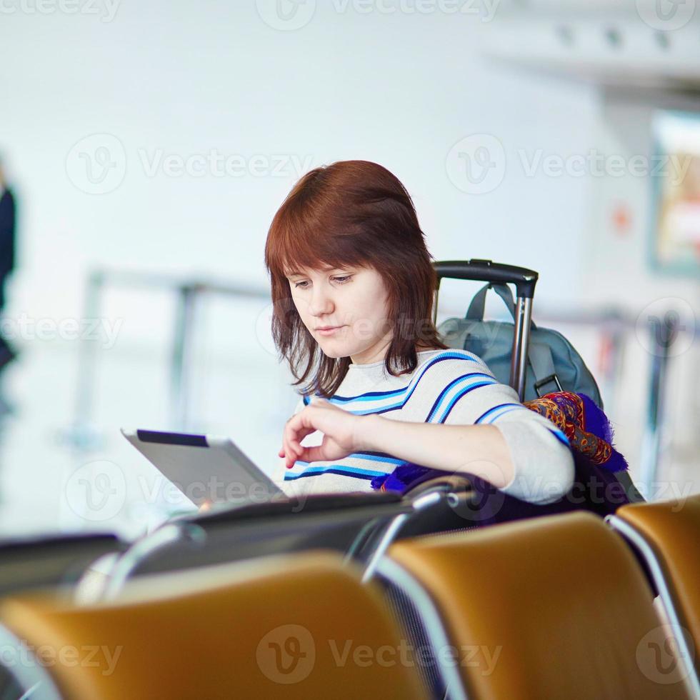 jovem passageiro no aeroporto, usando seu tablet foto