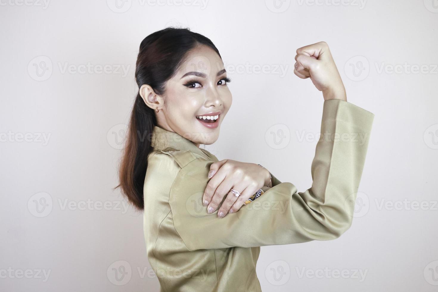 linda jovem asiática forte vestindo um uniforme marrom e mostrando bíceps e sorrindo. conceito forte de garota indonésia. foto