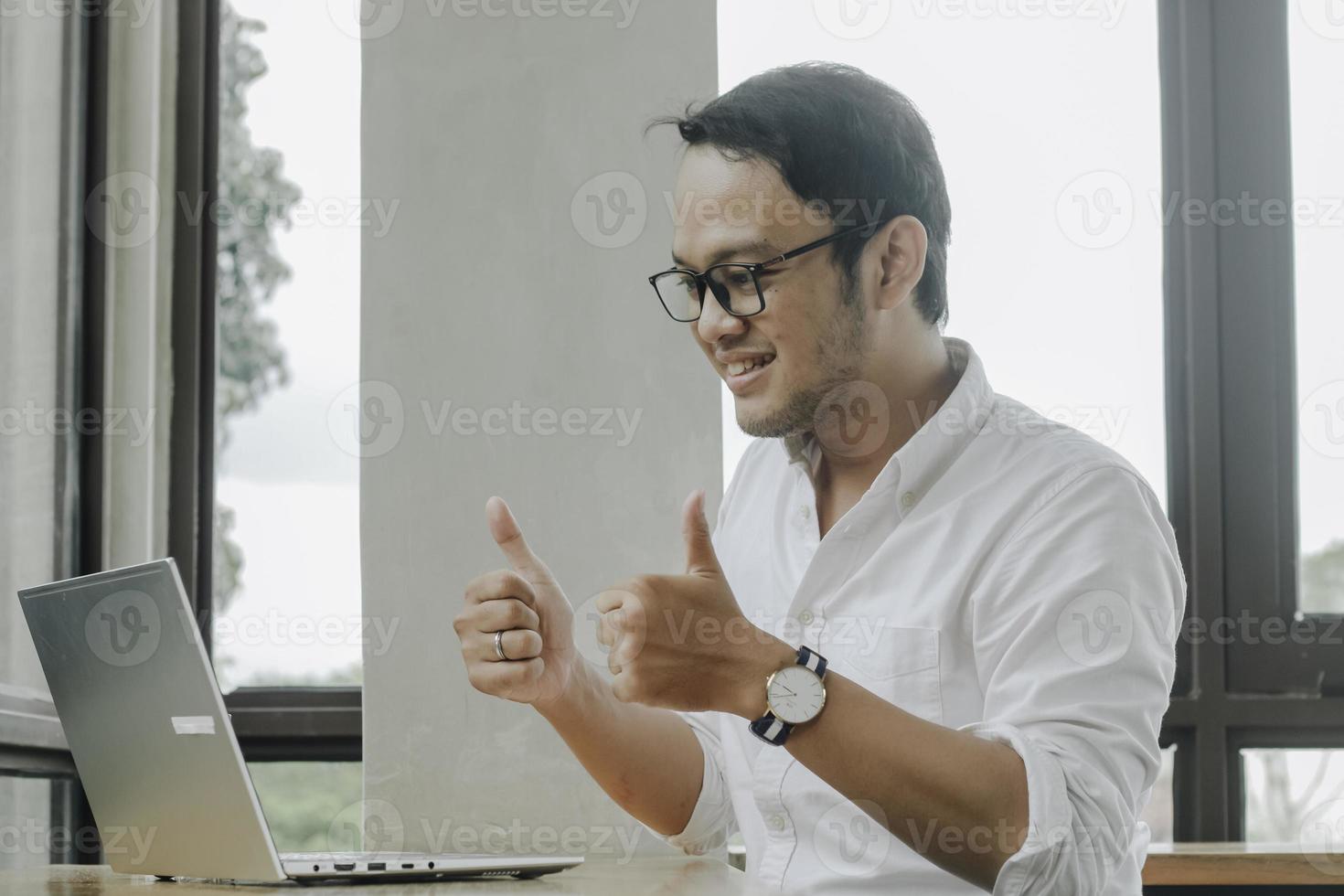 jovem asiático fazendo videoconferência no computador portátil enquanto está sentado no café, tendo reunião foto