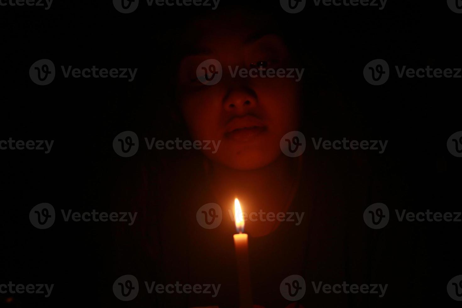 uma mulher asiática assustadora com vela na noite escura foto