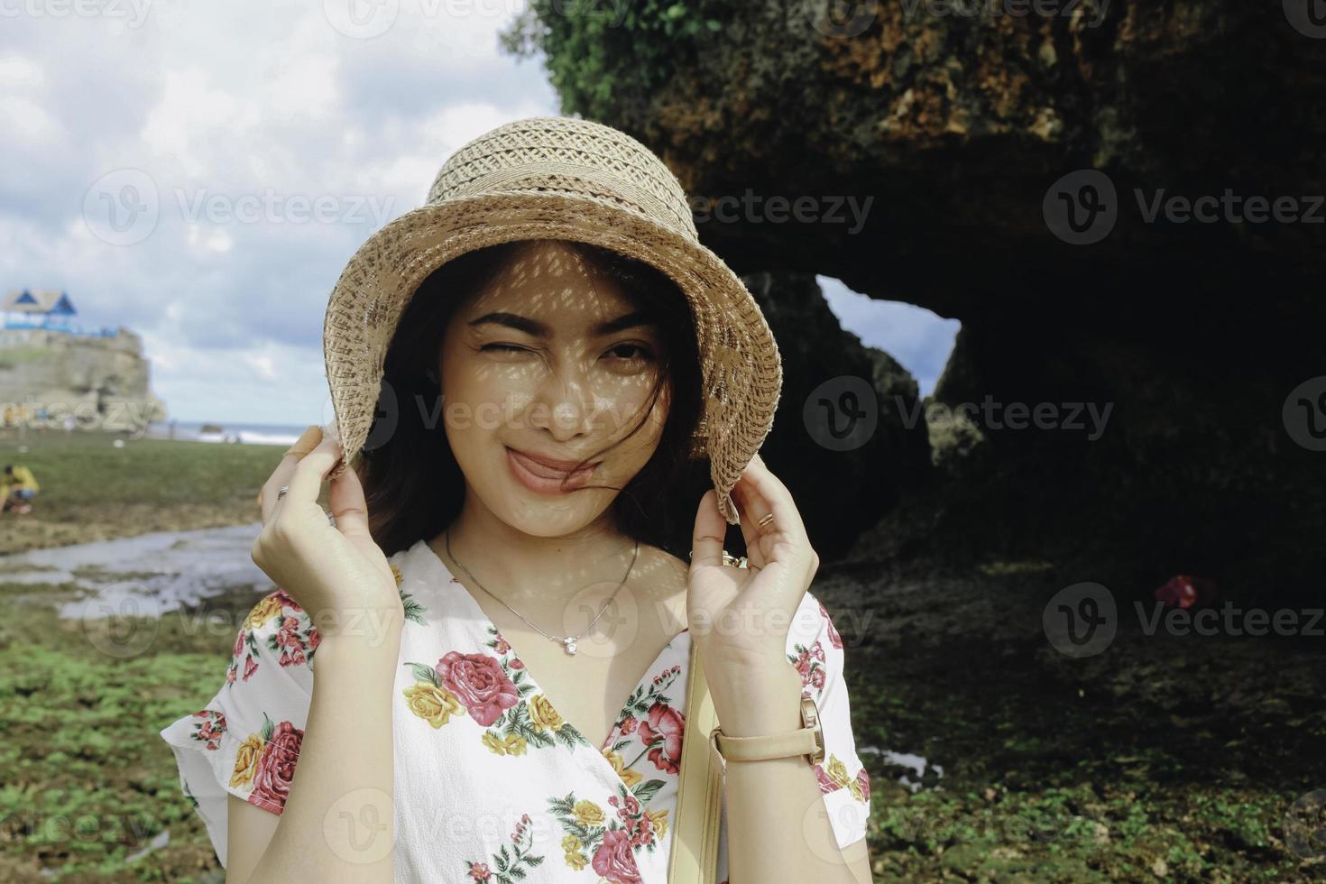 uma jovem garota asiática bonita usando um chapéu de sol está relaxando na praia de céu azul em gunungkidul, indonésia foto