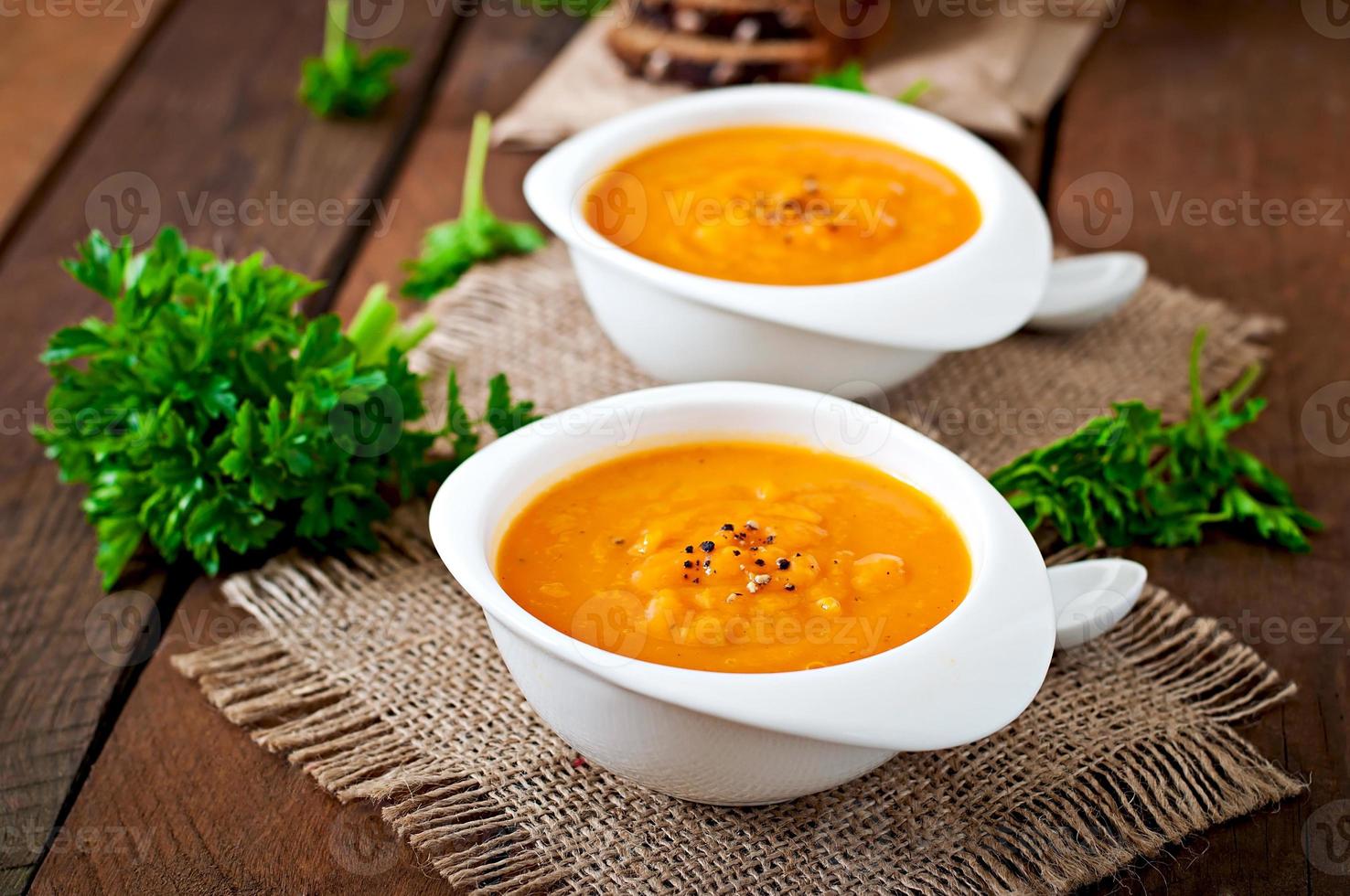 delicioso creme de sopa de abóbora em uma tigela na mesa de madeira foto