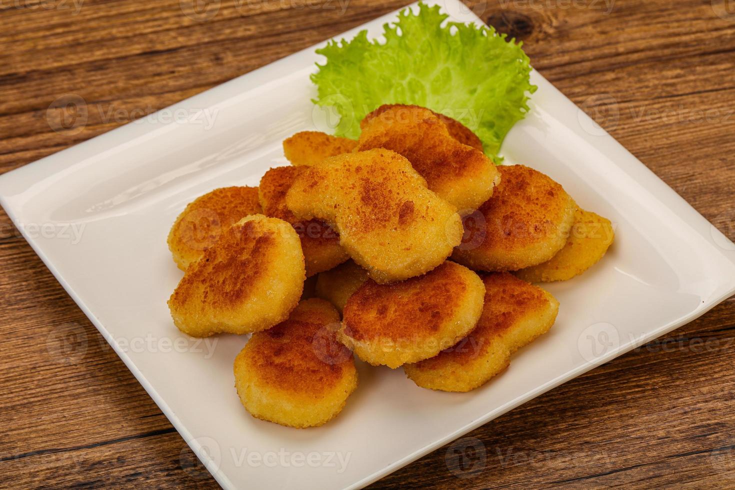 nuggets de frango frito servido com folhas de salada foto