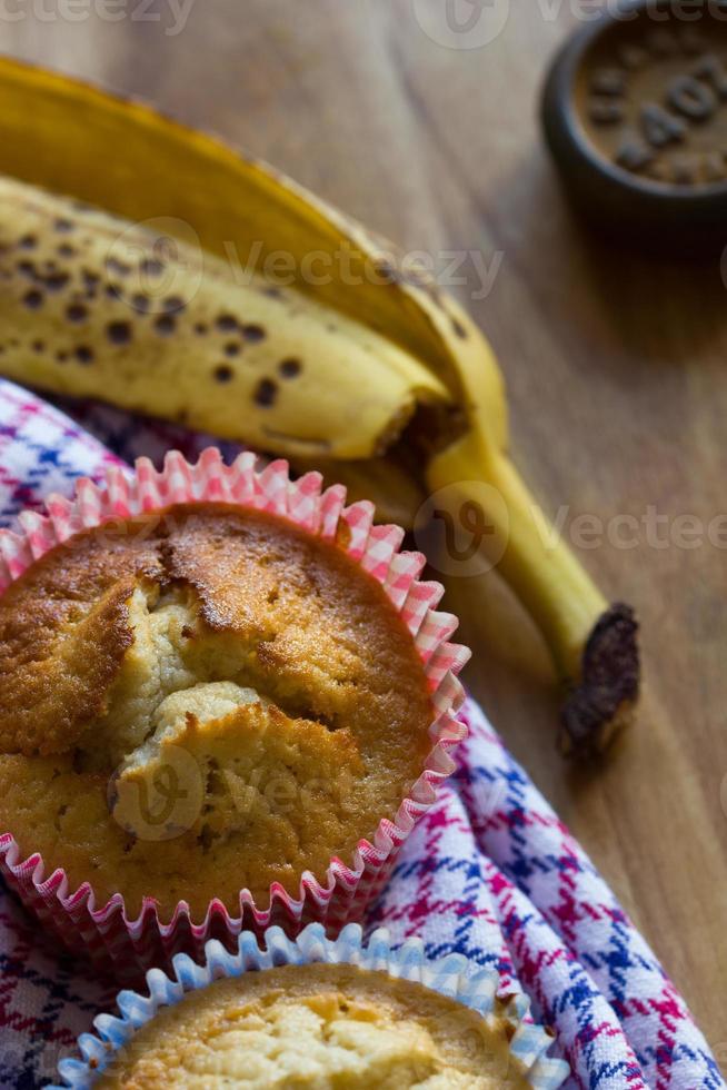 muffins de banana, pele de banana, pano e peso em fundo madeira foto