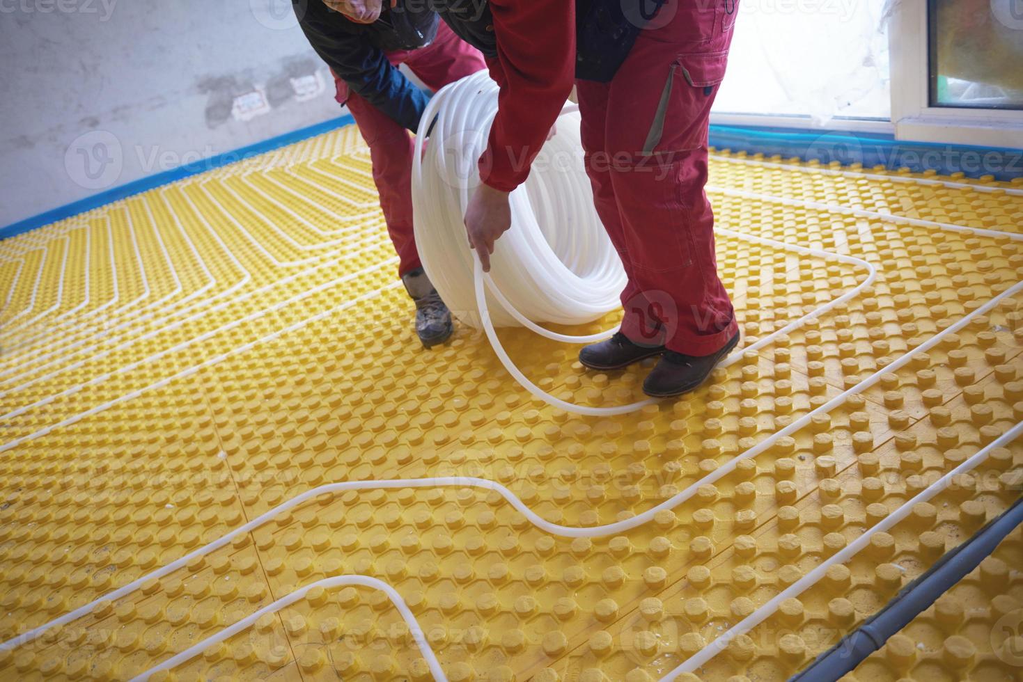 trabalhadores instalando sistema de piso radiante foto