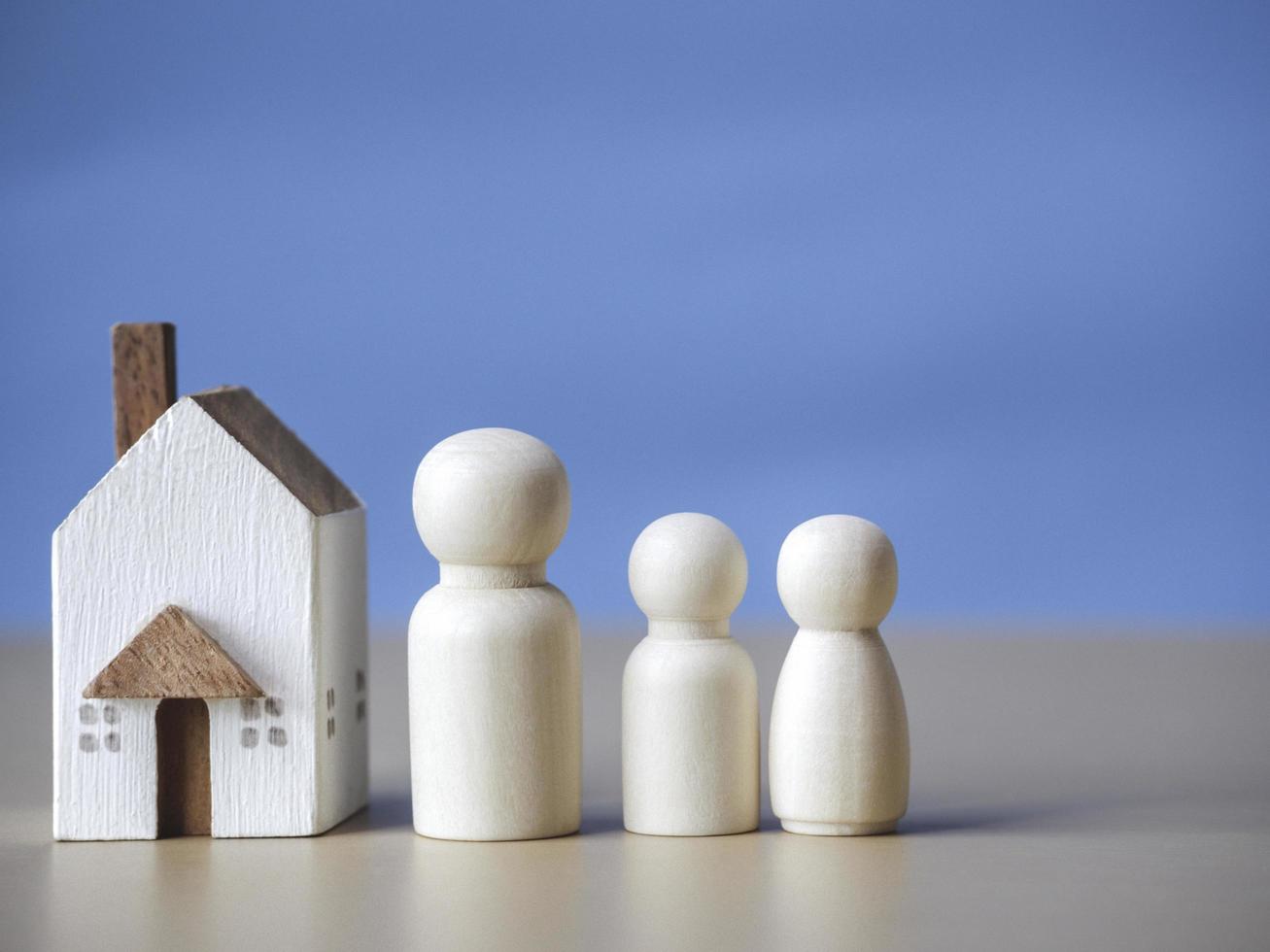 três figuras de madeira pessoas nas proximidades da pequena casa de madeira. conceito para família, empréstimo, escada de propriedade, financeiro, hipoteca, investimento imobiliário, impostos e bônus. foto