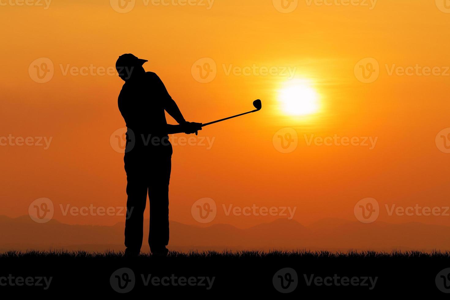 silhueta de um jogador de golfe balançando ao pôr do sol foto