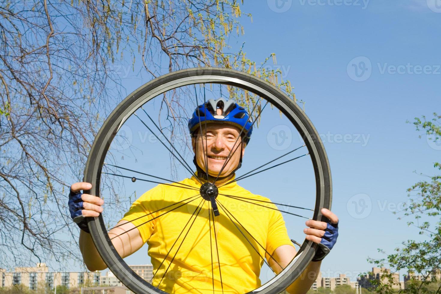 senior sorridente, olhando através de um pneu de bicicleta foto
