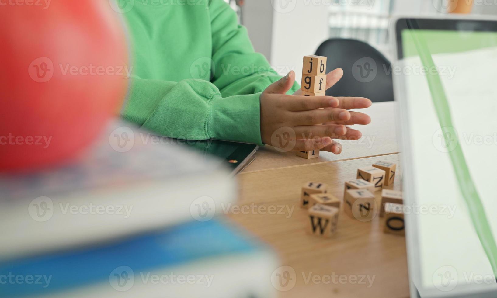 estudante afro-americano fazendo atividade jogando bloco de madeira para desenvolvimento junto com diversão e diversão em sala de aula. foto