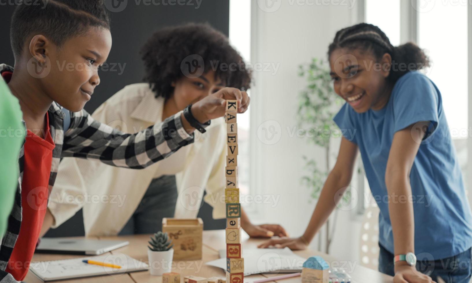 professor americano africano e aluno fazendo atividade jogando bloco de madeira para desenvolvimento junto com diversão e diversão em sala de aula. foto