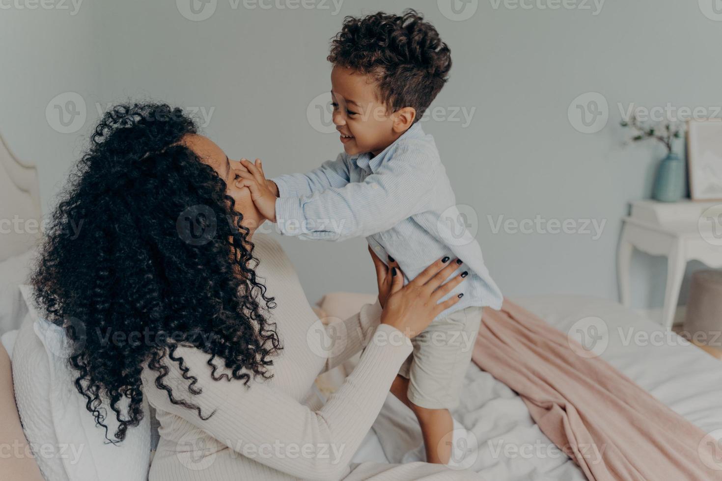 senhora afro-americana grávida brincando com seu filho em casa foto