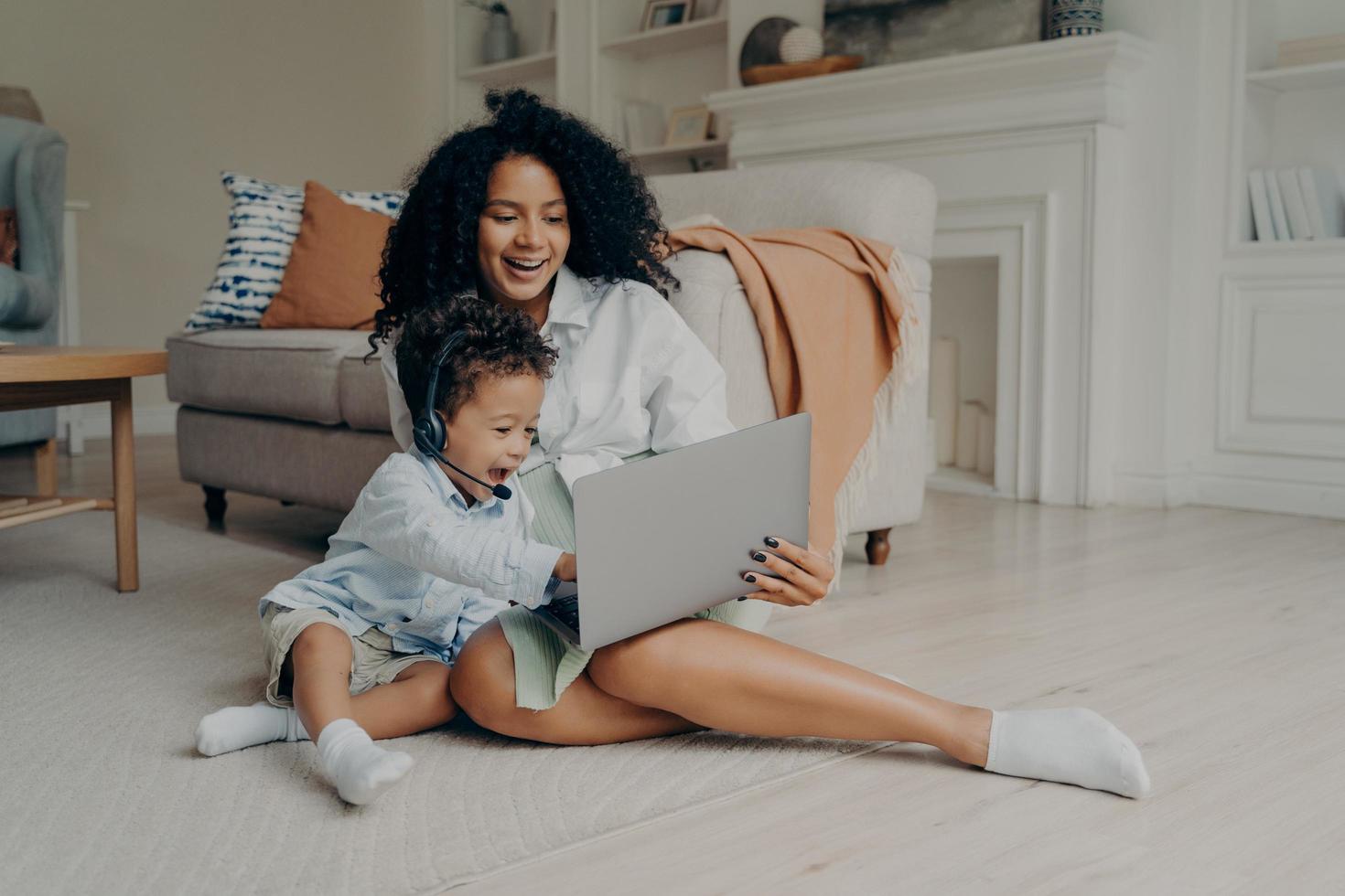 jovem mãe de raça mista positiva e filho bonitinho tendo chamada de vídeo no laptop foto