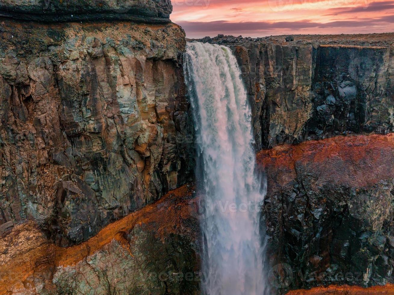 vista aérea na cachoeira hengifoss com sedimentos de listras vermelhas na islândia. foto