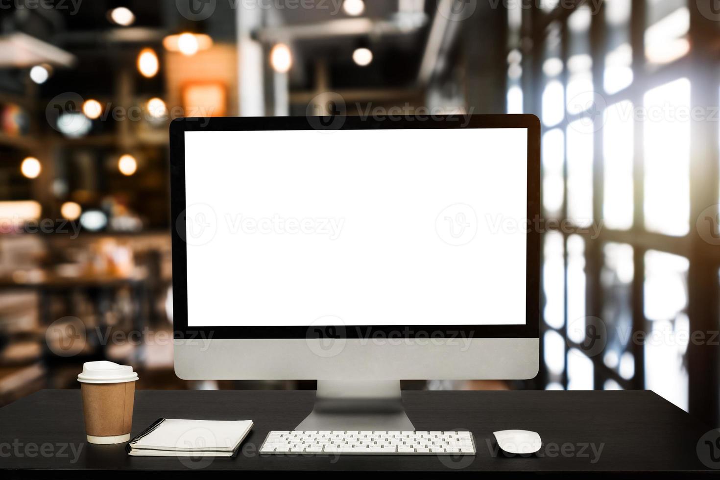 monitor de computador, teclado, smartphone de xícara de café, tablet e mouse com tela em branco ou branca isolada está na mesa de trabalho na cafeteria foto