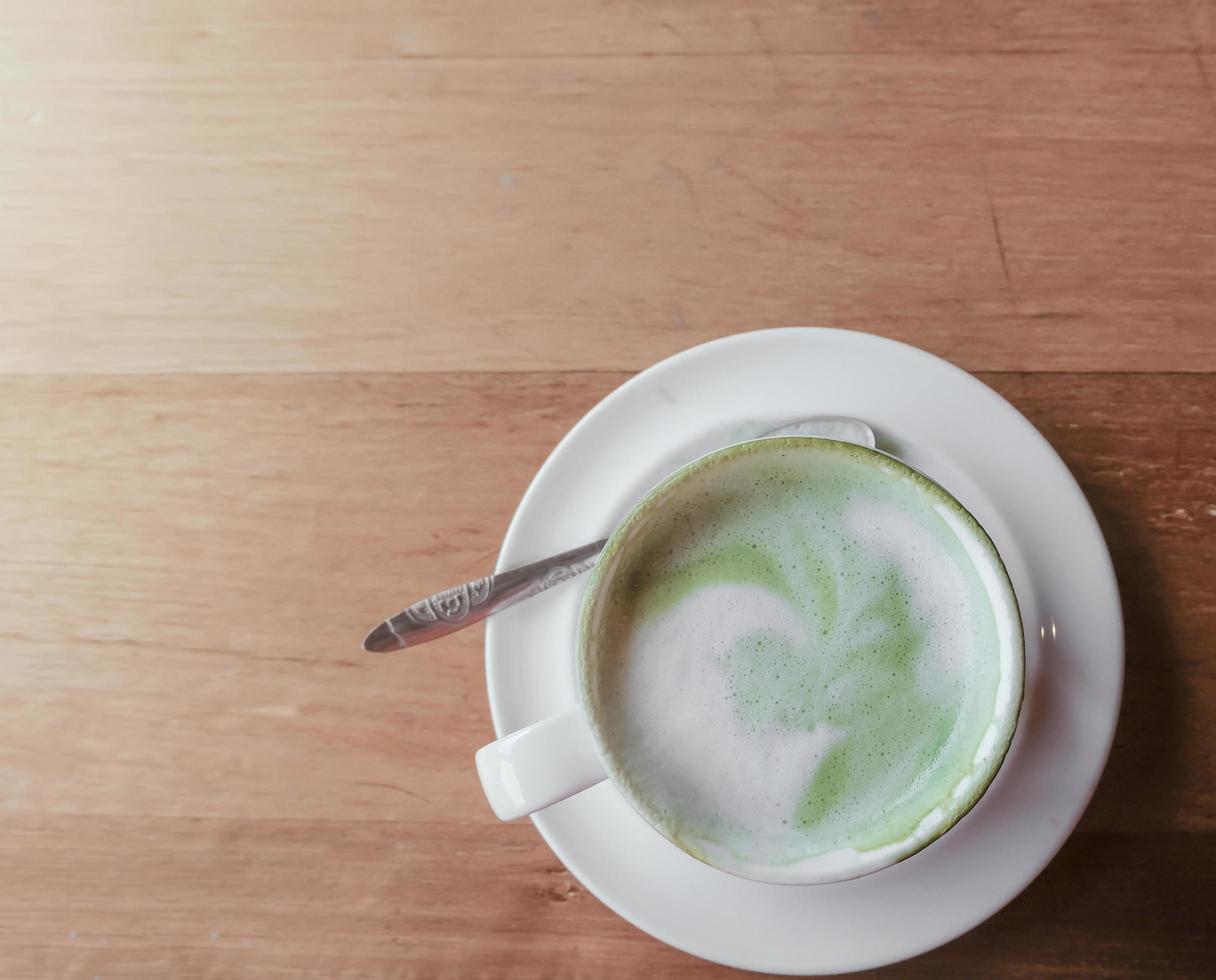 vista superior com leite quente de chá verde no fundo da mesa de madeira à tarde, efeito de luz foto