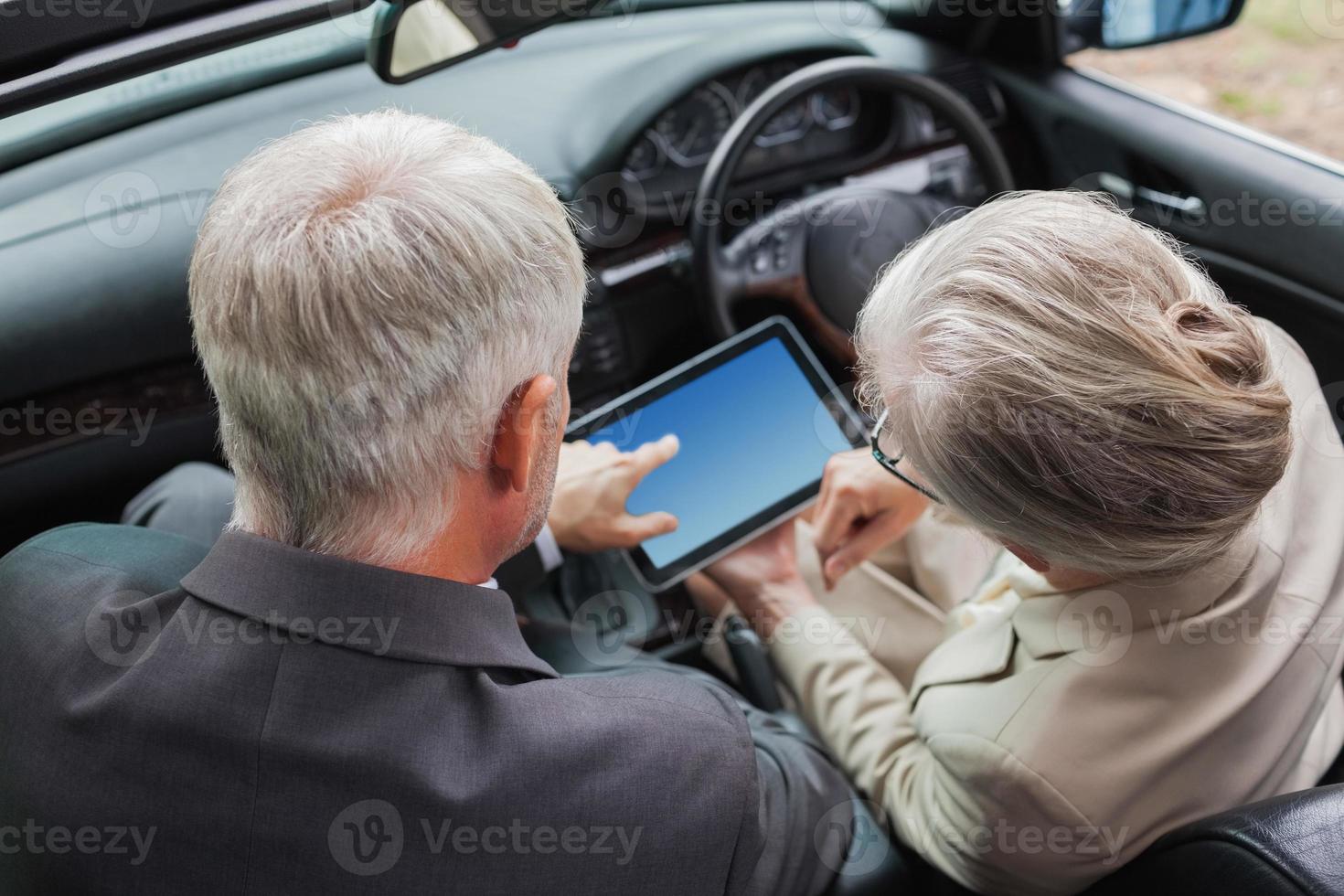 parceiros maduros trabalhando juntos em tablet no carro elegante foto