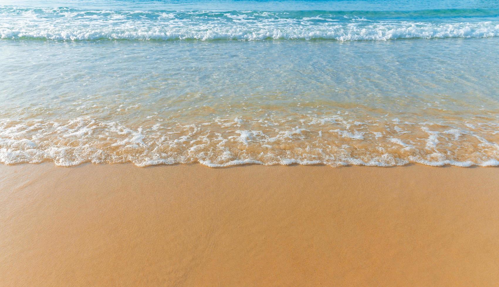 bela praia de areia e onda do mar de água na areia foto