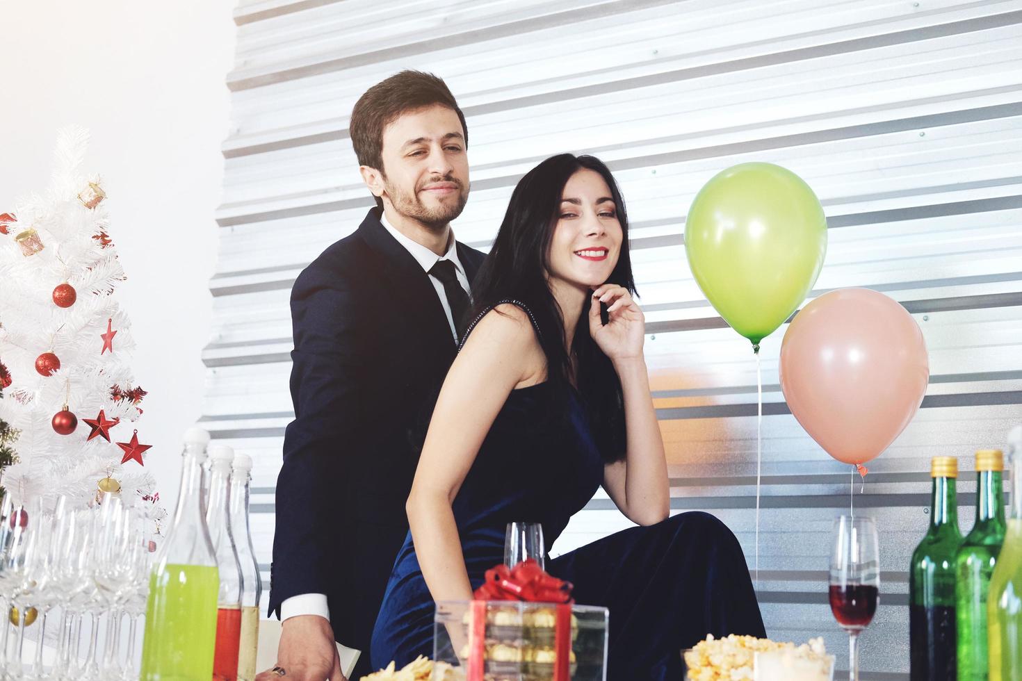 doce casal adora sorrir e passar romântico bebendo vinho na época do natal e comemorando a véspera de ano novo, dia dos namorados com balão colorido e caixas de presente na despensa foto