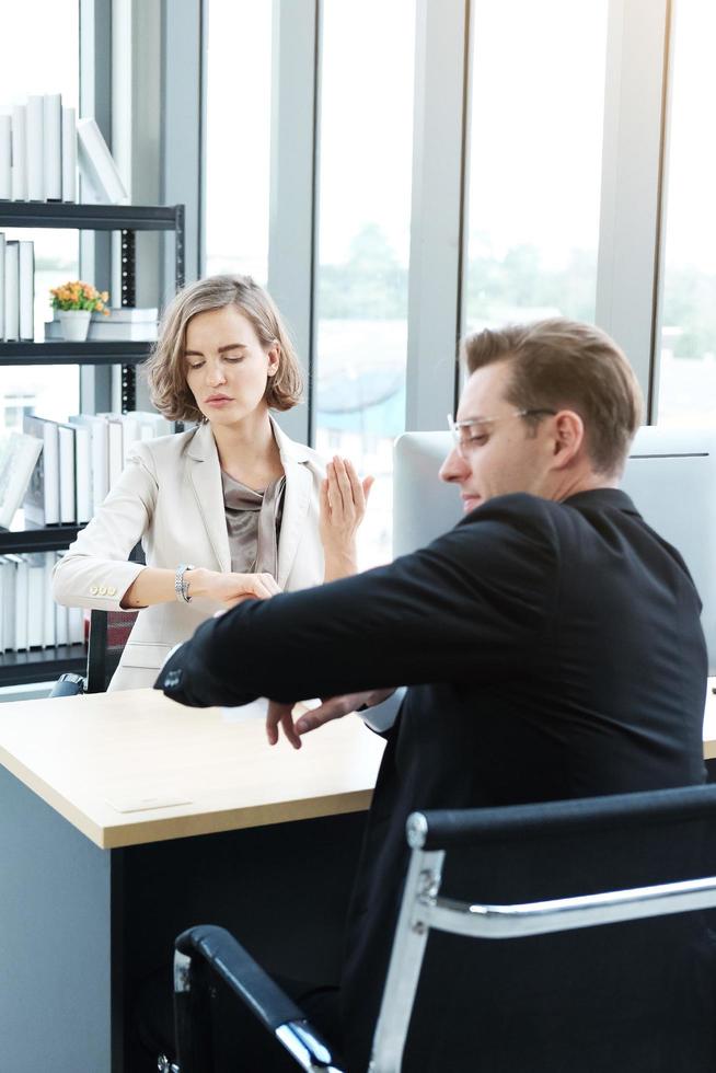 empresário de sucesso e empresária assistem relógio de pulso e sério sobre negócios importantes para fazer após a reunião no escritório foto