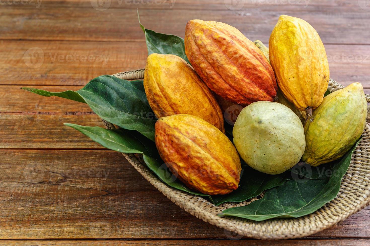 frutas de cacau em uma cesta em uma mesa de madeira foto