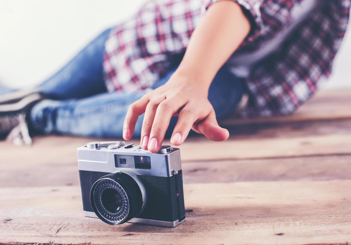 mulher jovem fotógrafo hipster tirando foto e olhe para a câmera sentada no chão de madeira.