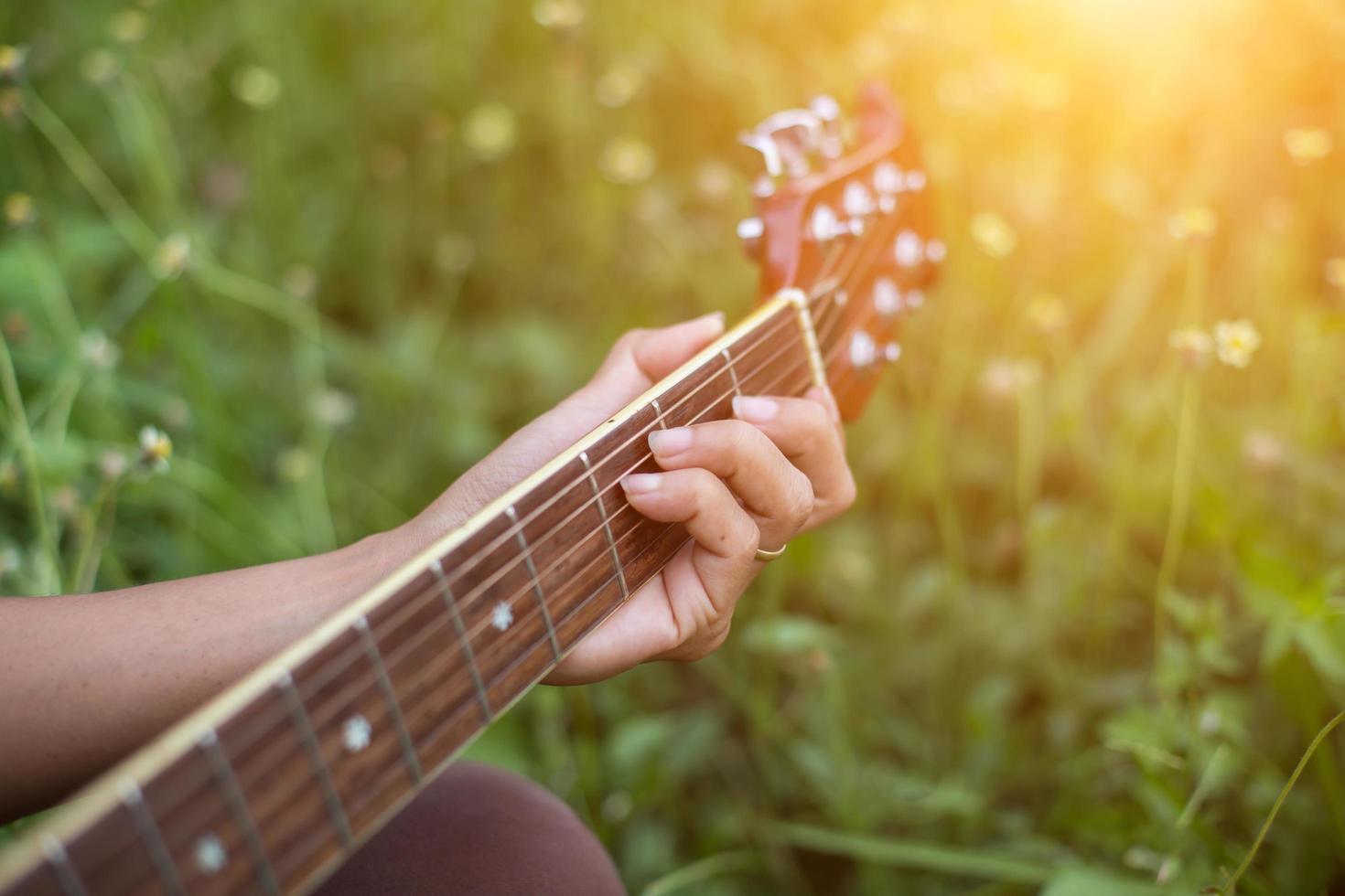 mulher jovem hippie tocando violão para relaxar em suas férias, divirta-se com ar natural e fresco. foto