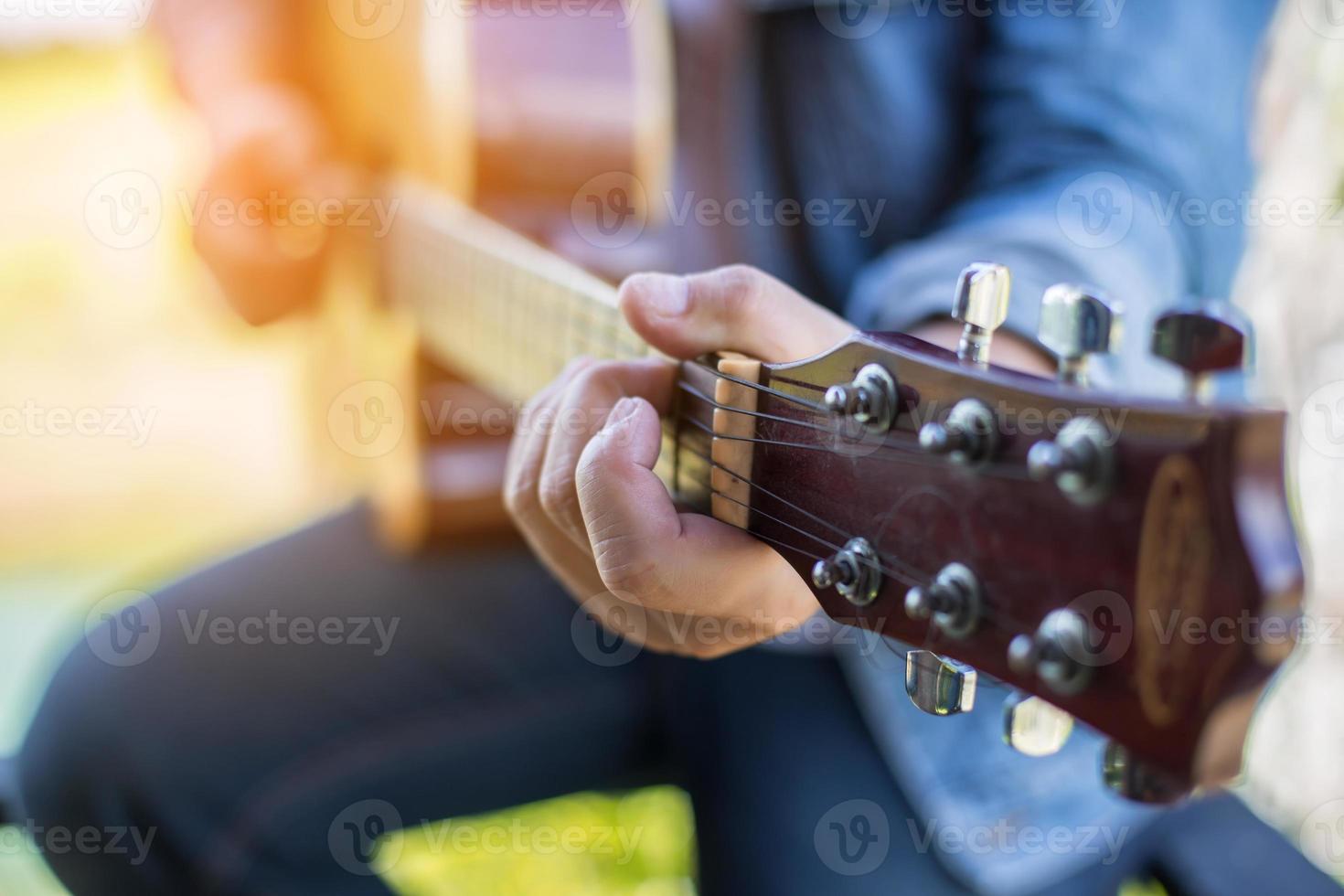 homem jovem hippie tocando guitarra para relaxar em suas férias, divirta-se com ar natural e fresco. foto