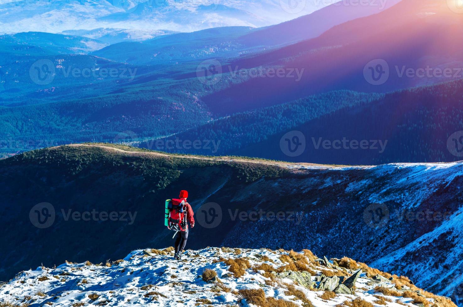 alpinista andando nas montanhas de inclinação de neve e sol brilhando foto