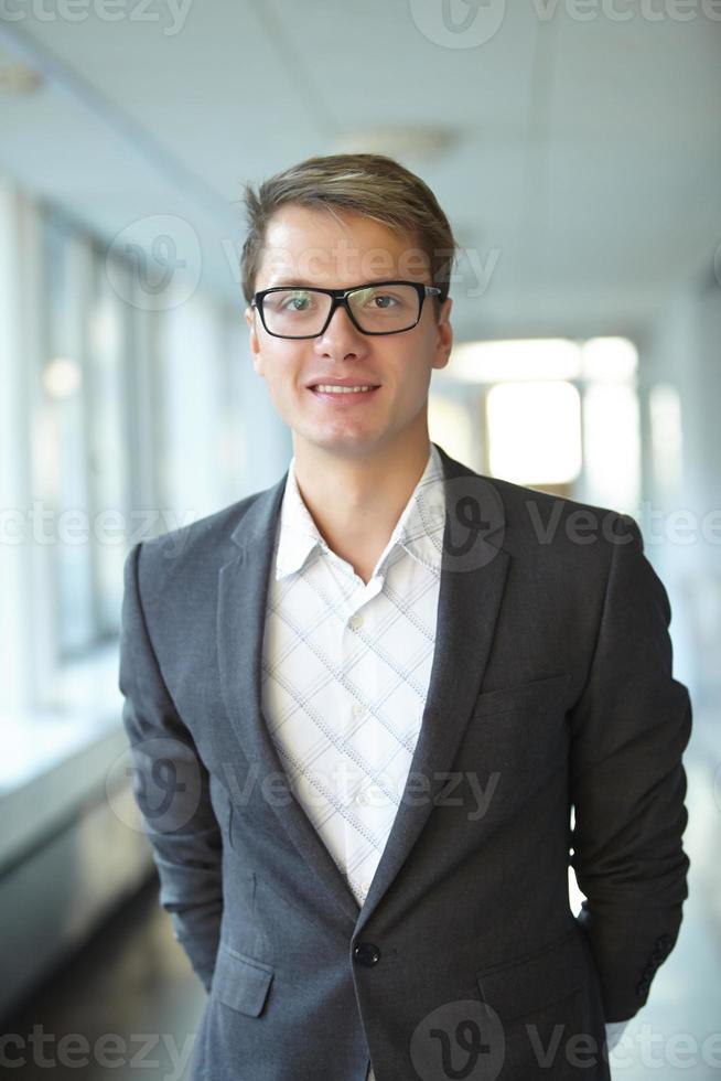 jovem empresário de óculos em pé no corredor foto