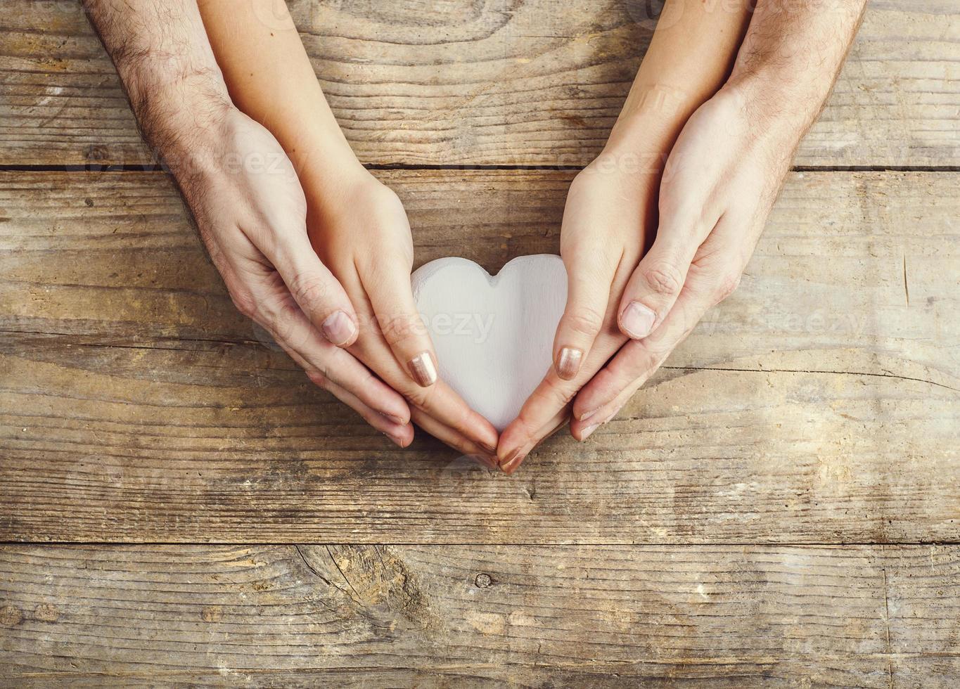 mãos de homem e mulher segurando um coração juntos. foto