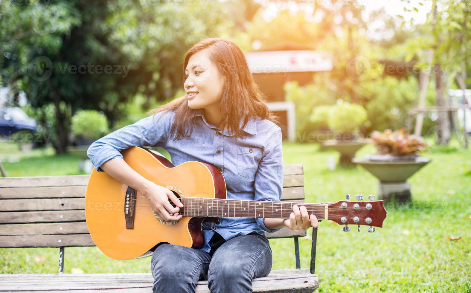 mulher jovem e bonita tocando violão sentado no banco, conceito de tempo feliz. foto