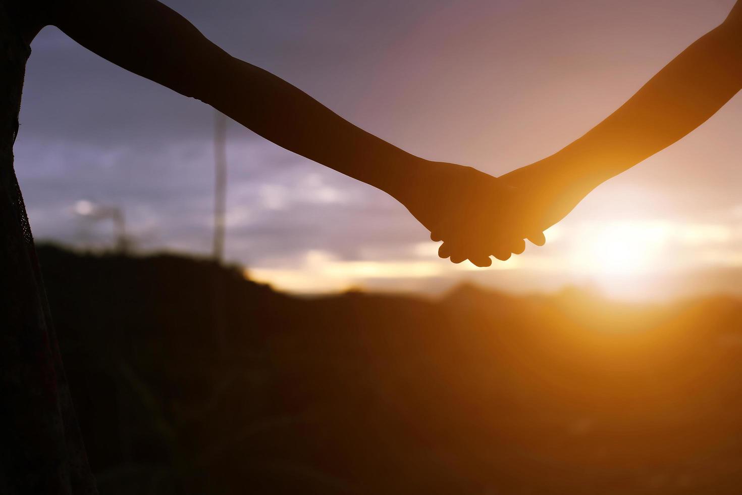 jovem casal de mãos dadas. na natureza nascer do sol foto