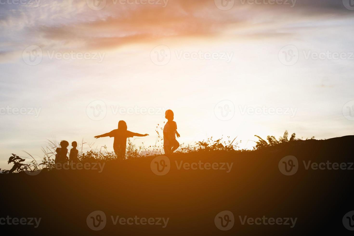 silhueta de crianças felizes e pôr do sol de tempo feliz foto