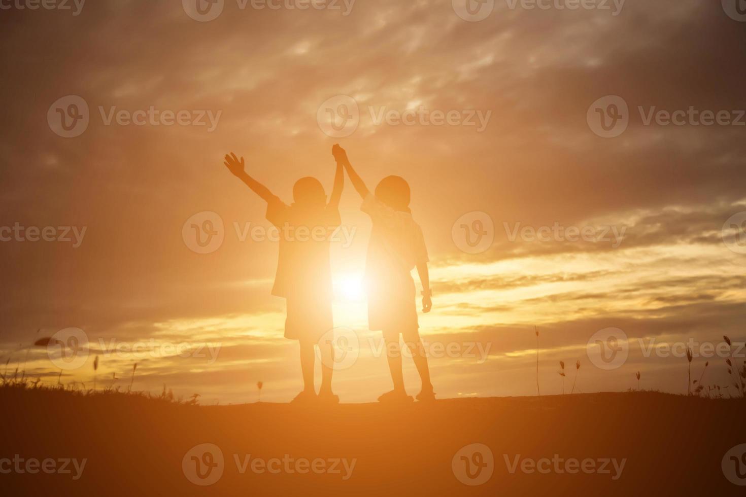 silhueta de crianças felizes e pôr do sol de tempo feliz foto