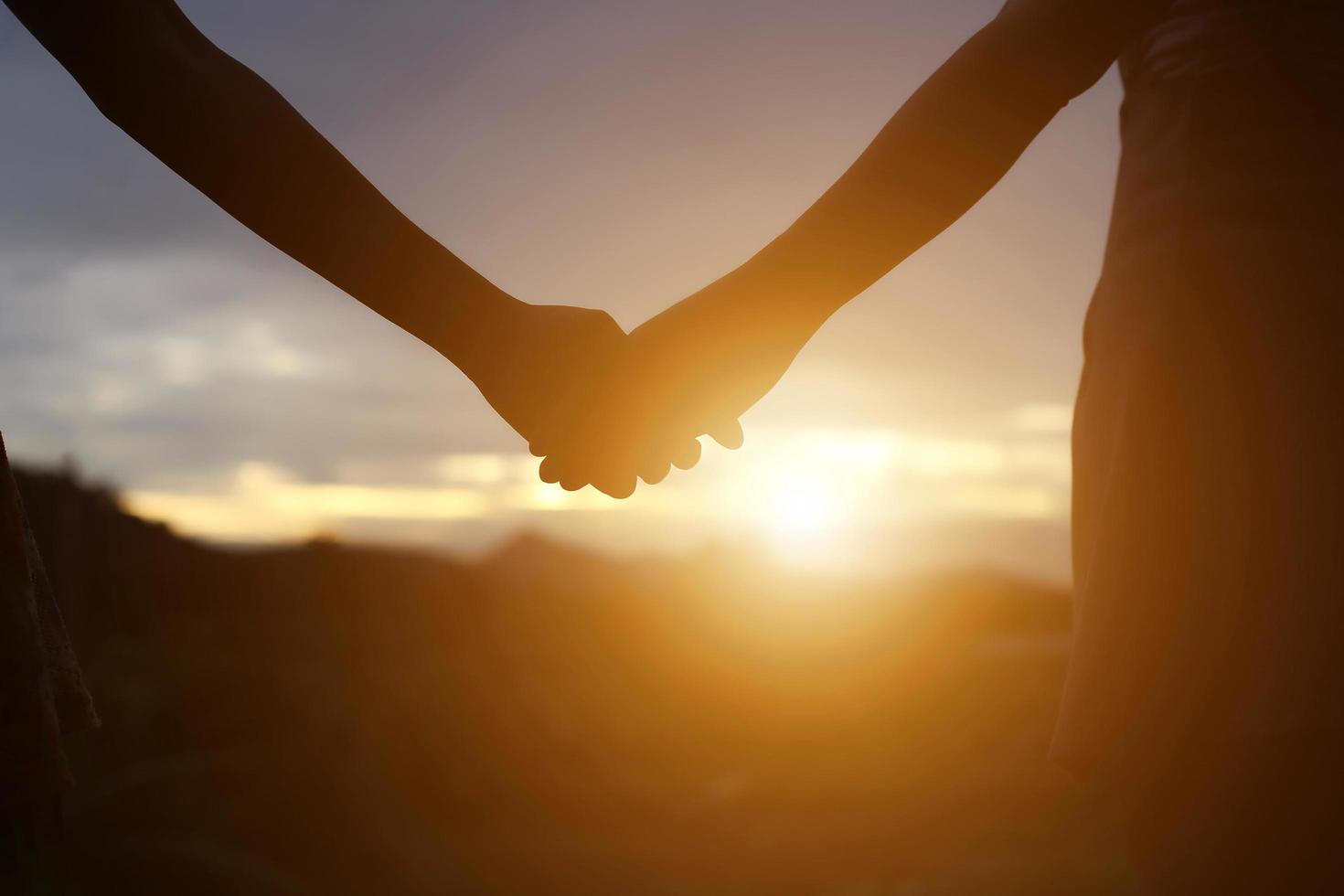 jovem casal de mãos dadas. na natureza nascer do sol foto