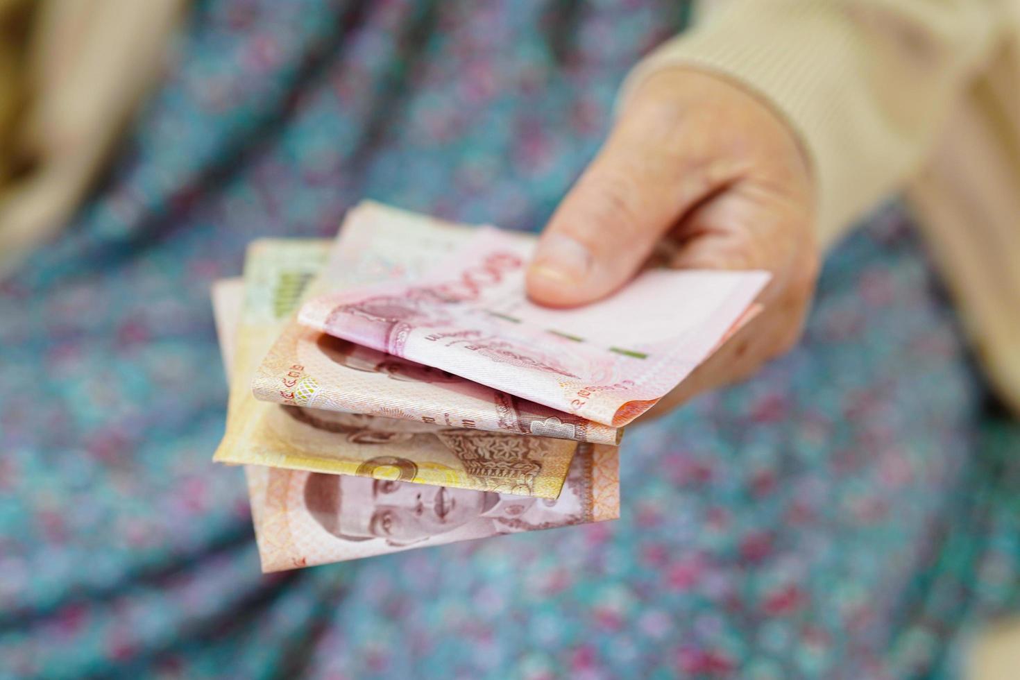 paciente asiática idosa idosa segurando notas de dinheiro na mão, custo de vida e cuidados médicos. foto