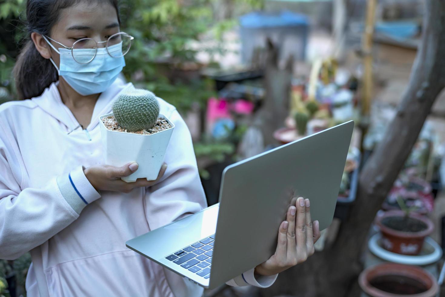linda garota asiática trabalhadora de estufa vendendo pequenas plantas na mídia social transmissão ao vivo com celular. paisagismo de pequenas árvores e jardineiro de decoração de jardim doméstico. foto
